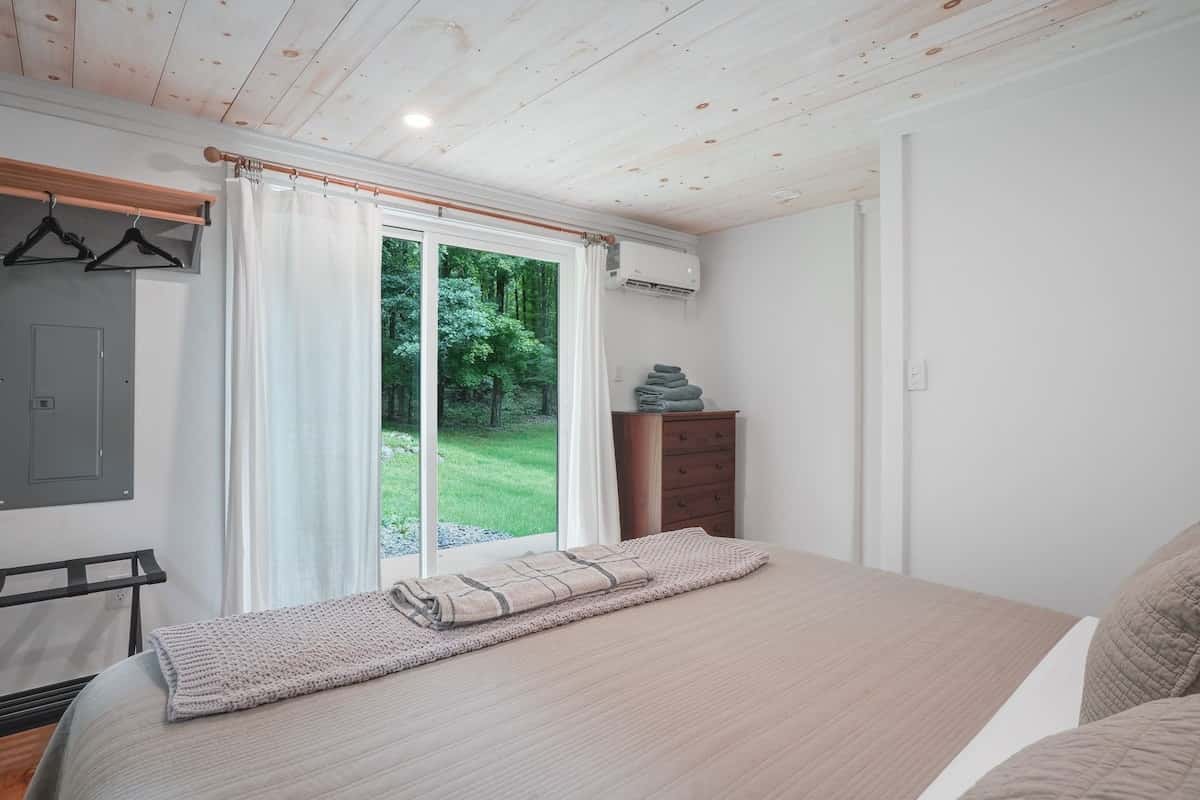 The bedroom's sliding glass doors open to the lawn, curtains drawn back